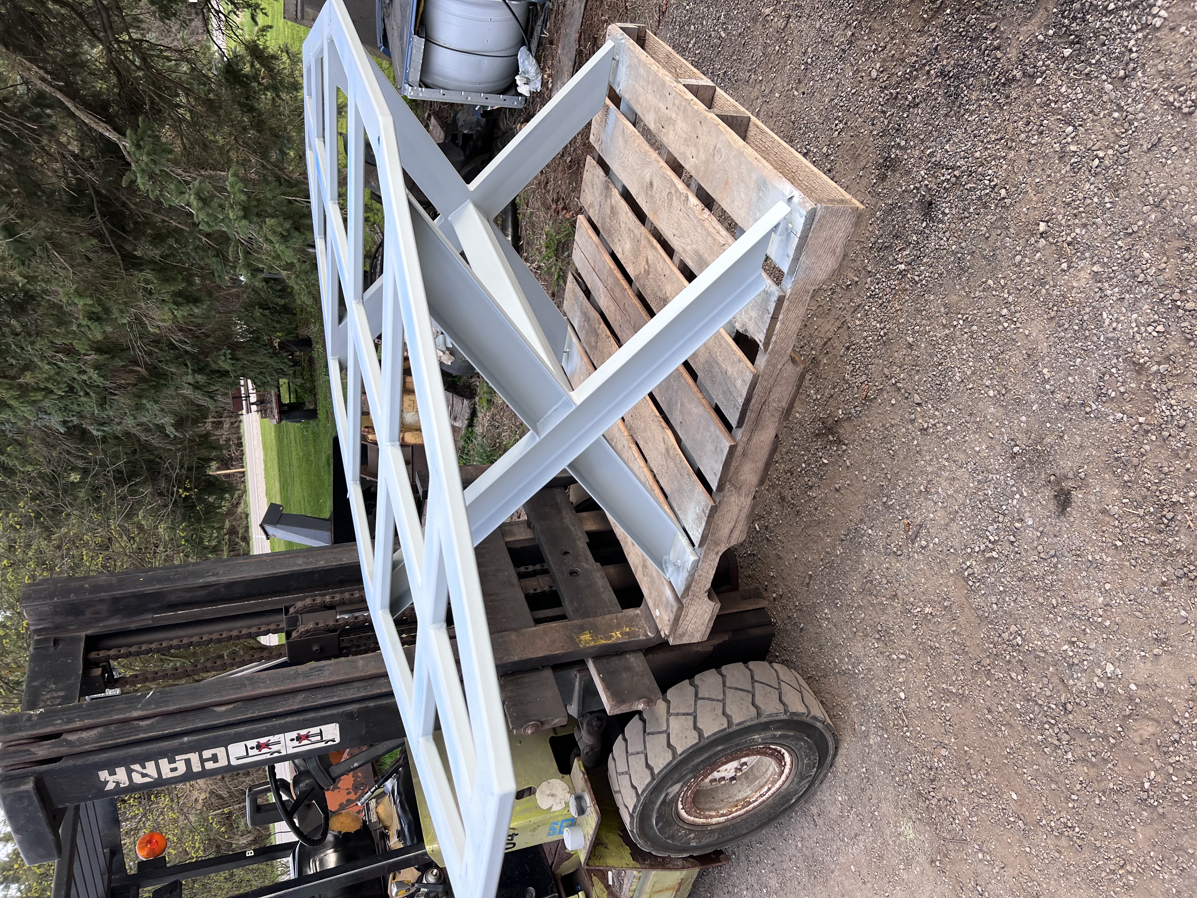 Fabricated metal frame (similar to gallery20 but unpainted) resting on wooden pallets outdoors.