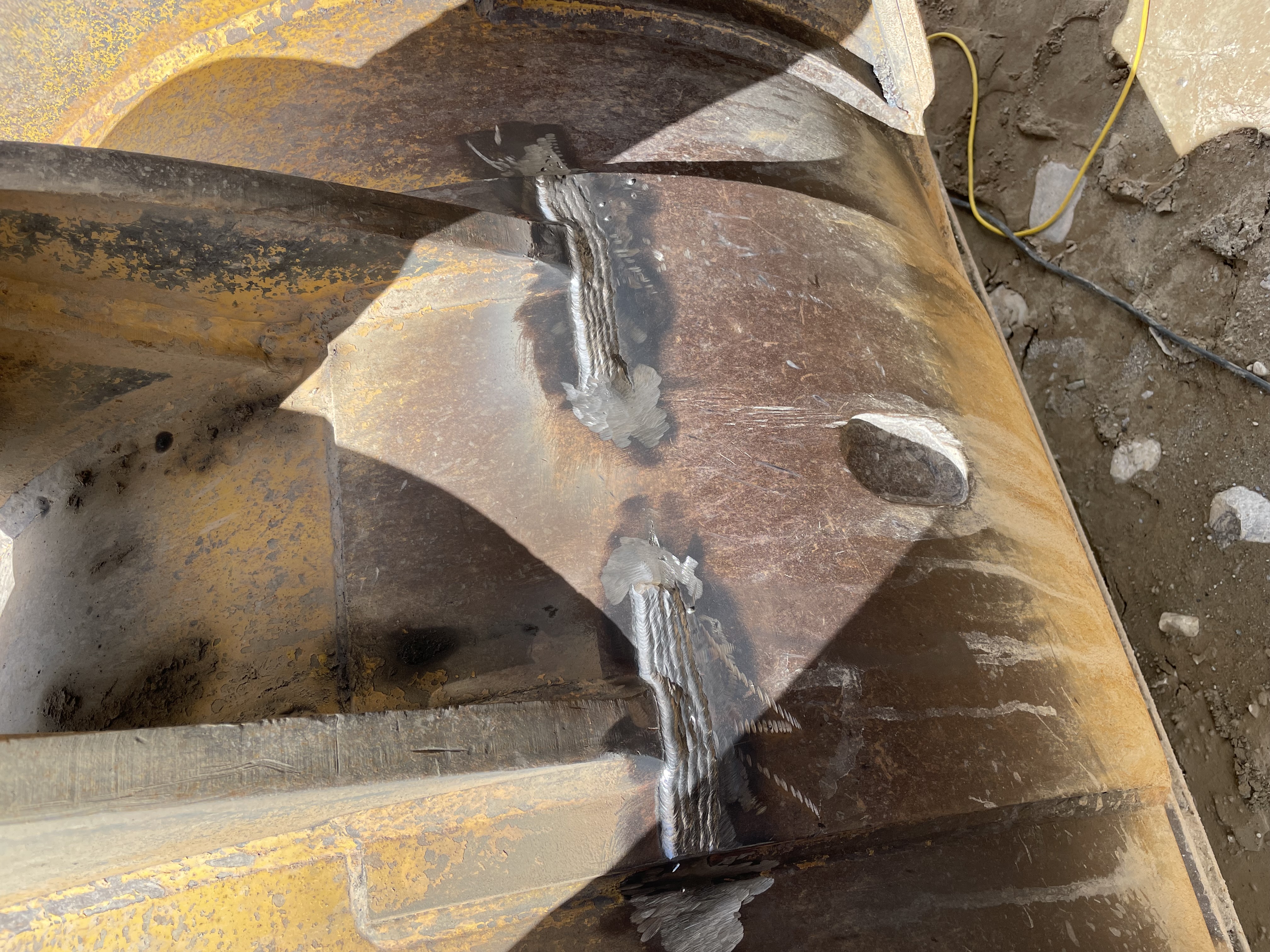Close-up of multiple welds joining structural steel angle iron pieces. Shows structural fabrication/repair.